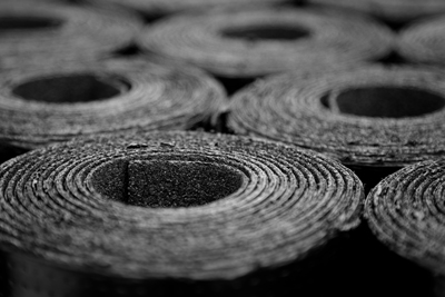 Close-up view of multiple rolls of black material, showcasing their circular shape and layered texture, often used in construction and insulation projects.