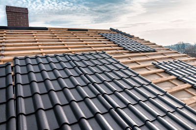 Roofing tiles installed on a wooden framework, showcasing a modern residential roof under a cloudy sky, with an emphasis on high-quality roof materials.